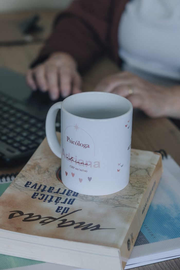 Psicologia del benessere Close-up of a psychologist's mug on books, next to a laptop on a desk.