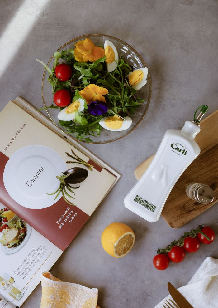 Flat lay of a fresh salad with eggs, flowers, and vegetables on a table.