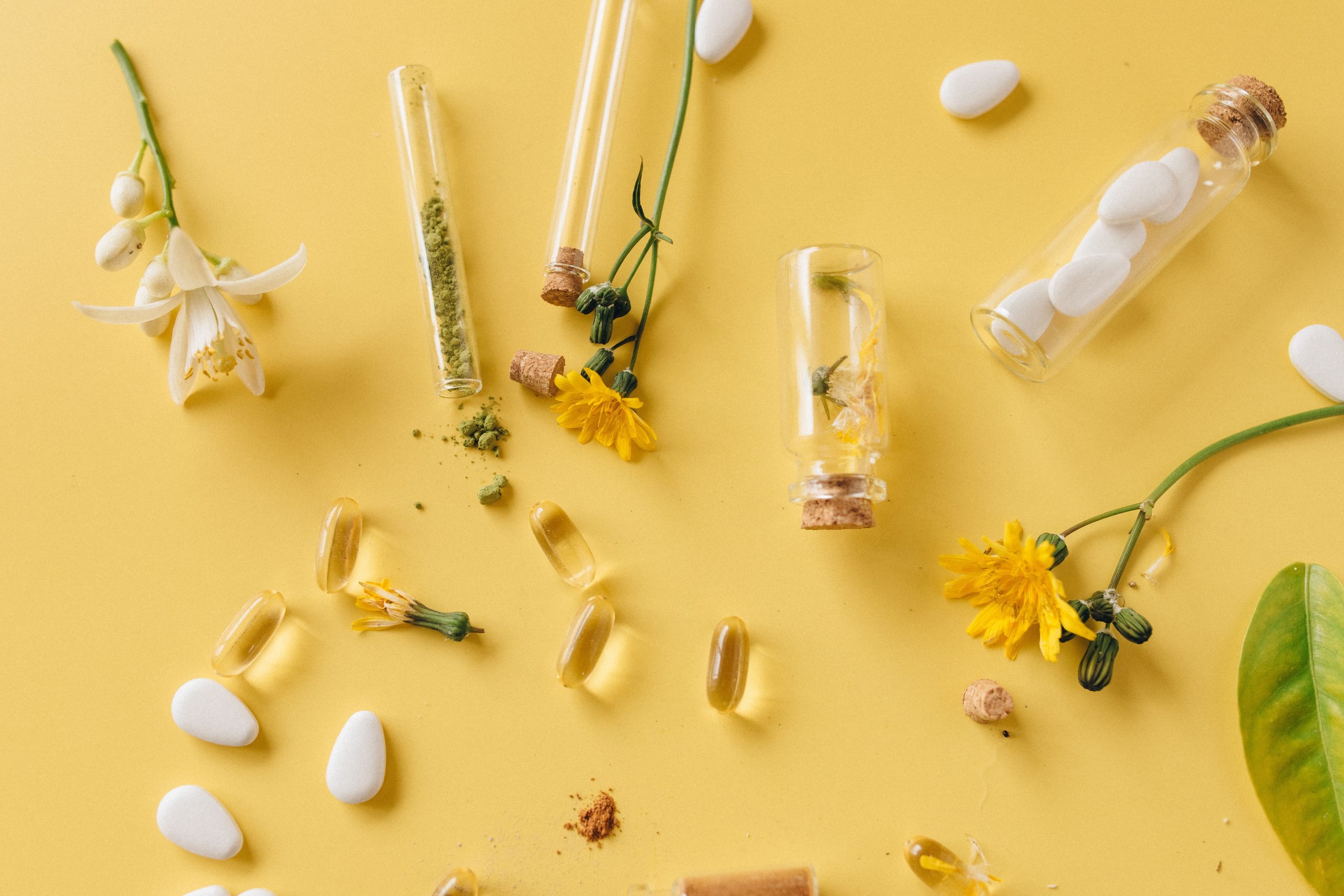 Negozio An arrangement of medicinal herbs, pills, and flowers on a vibrant yellow surface, highlighting natural healthcare.