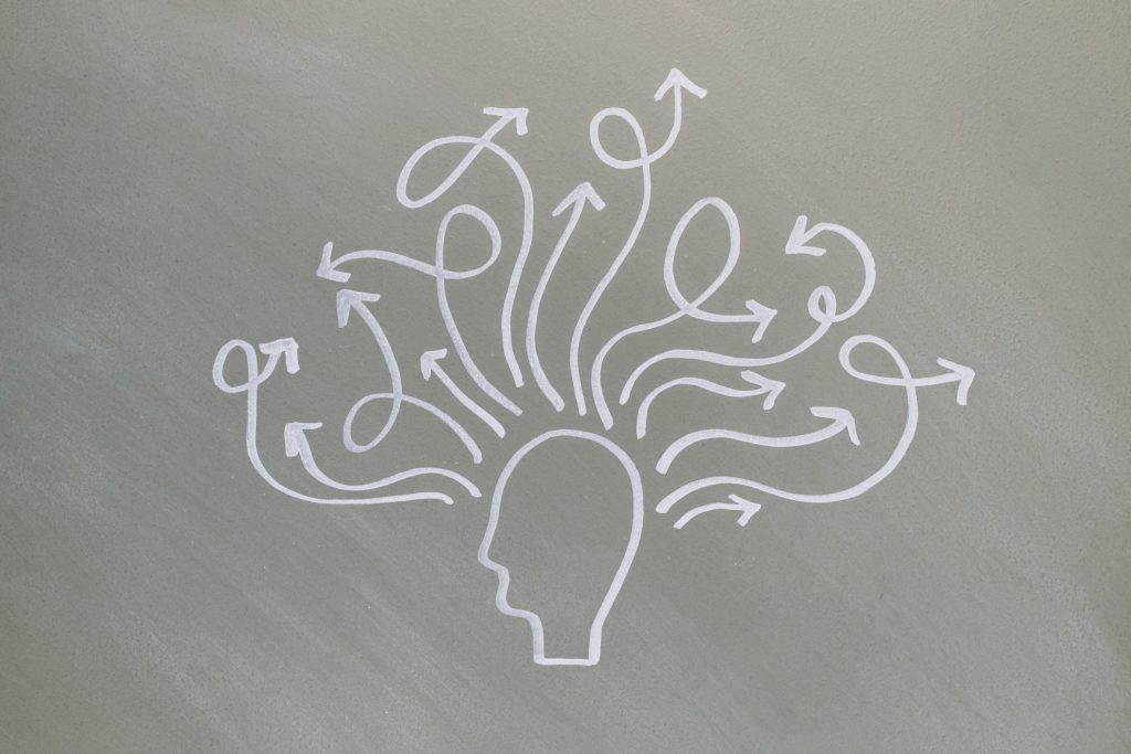Overthinking: come interrompere il ciclo dei pensieri Conceptual chalk drawing illustrating mental health challenges with arrows representing thoughts.