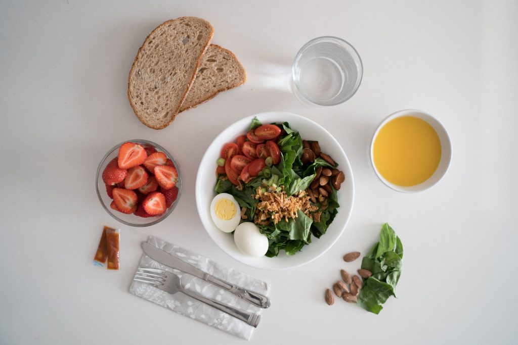 Alimentazione consapevole: mangiare bene senza rigidità Top view of a nutritious breakfast with salad, eggs, bread, and juice, perfect for a healthy start.