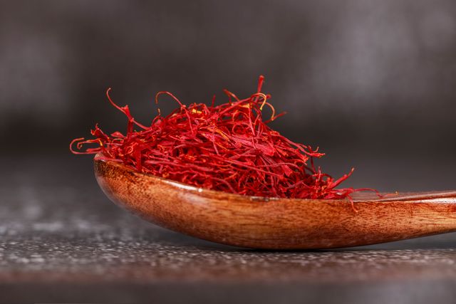 Zafferano: la spezia più preziosa, tra storia e produzioni italiane Detailed close-up of vibrant saffron threads in a wooden spoon, perfect for culinary imagery.