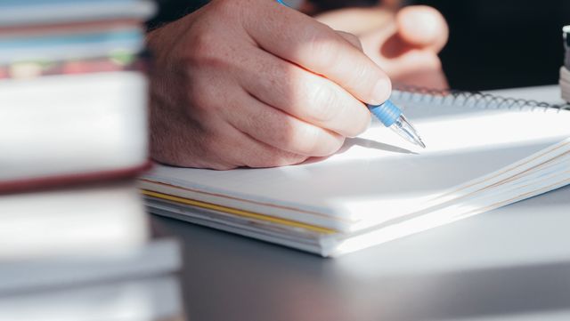 La pagina del mattino: svuotare la testa in 10 minuti A person writing notes with a pen in a bright, indoor setting.